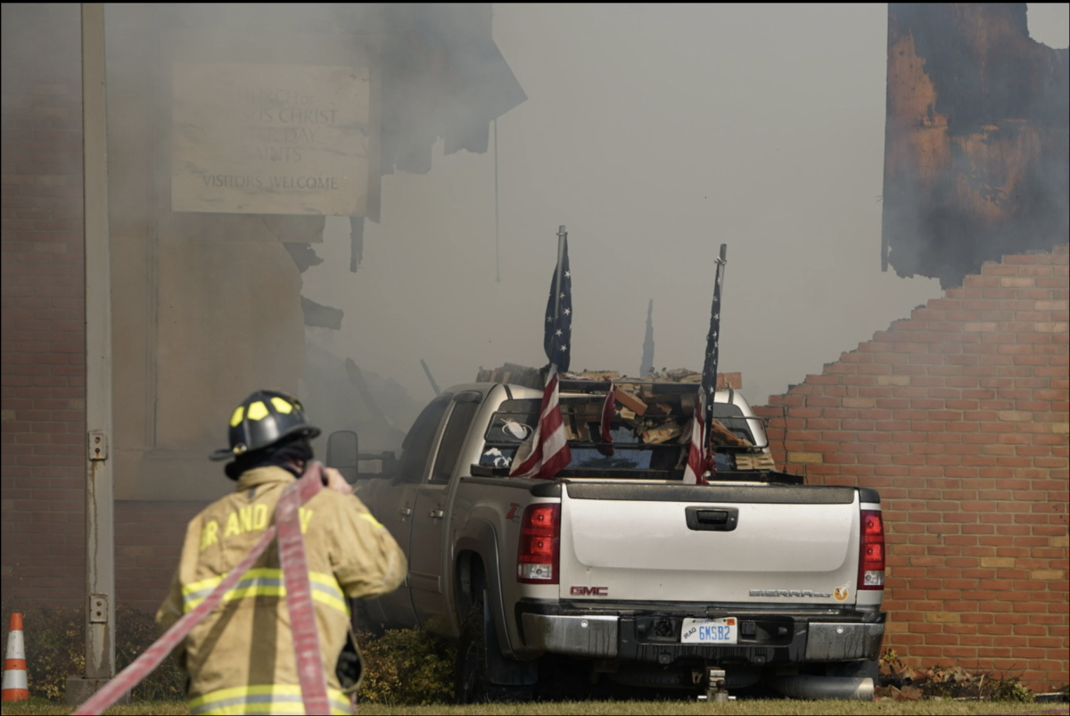 Vehicle rammed into the building is surrounded by smoke as a firefighter works on the scene at the church in Grand Blanc, Mich on Sept. 28 (Lukas Katilius/The Flint Journal via AP)
